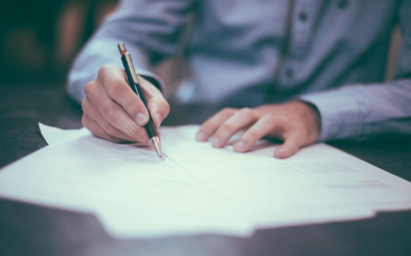 Pessoa a assinar um contrato com caneta