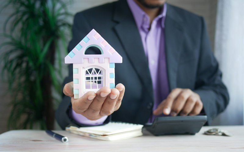Modelo de casa e calculadora sobre uma secretária