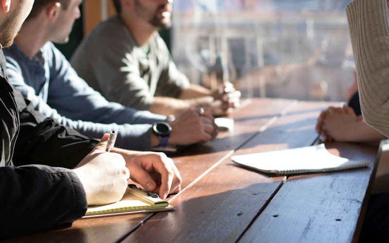 Reunião de trabalho à volta de uma mesa de madeira
